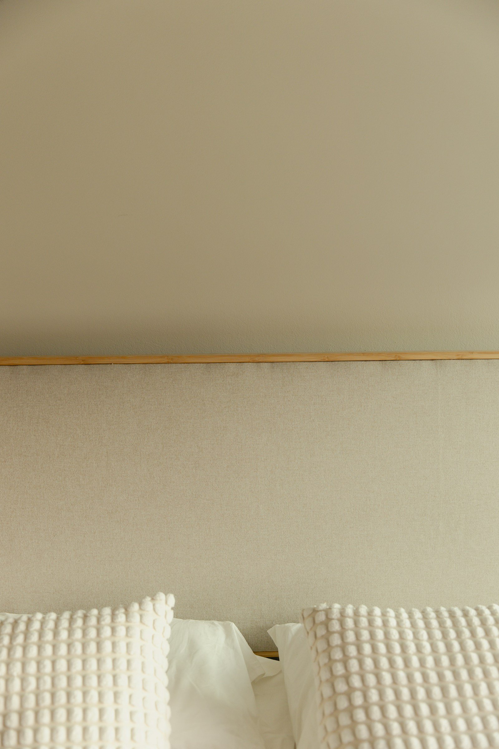 Beige bedroom idea with layered oatmeal linen bedding and soft neutral cushions