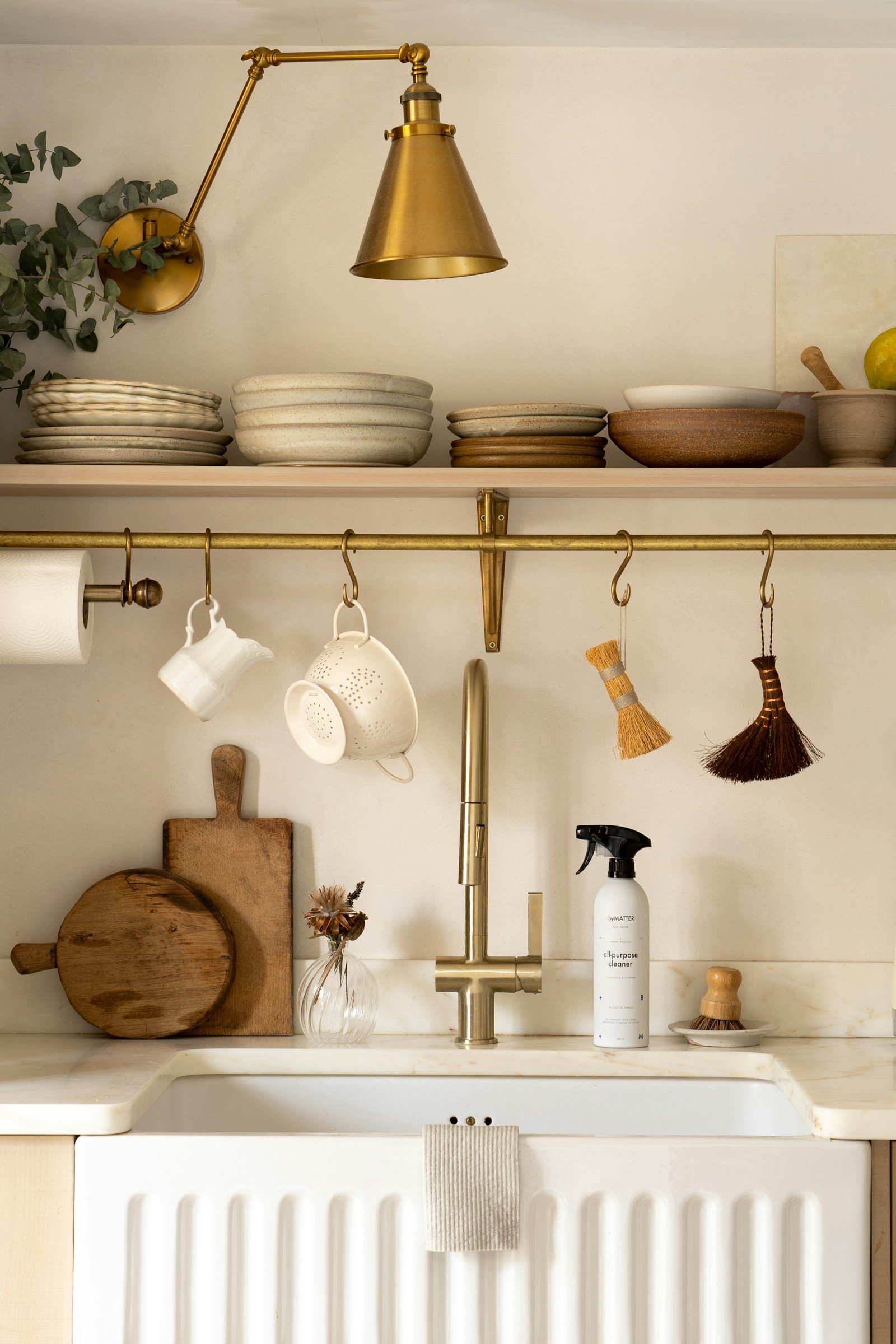 Beige kitchen idea with cream cabinets, a farmhouse sink and unlacquered brass faucet