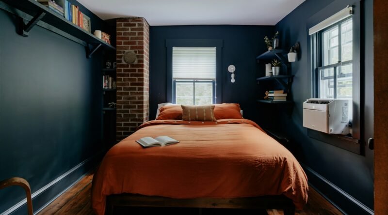 Dark bedroom with deep painted walls, warm lamplight and layered neutral bedding