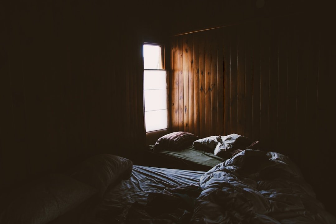 Cozy dark cabin bedroom with moody green tones and tousled bedding