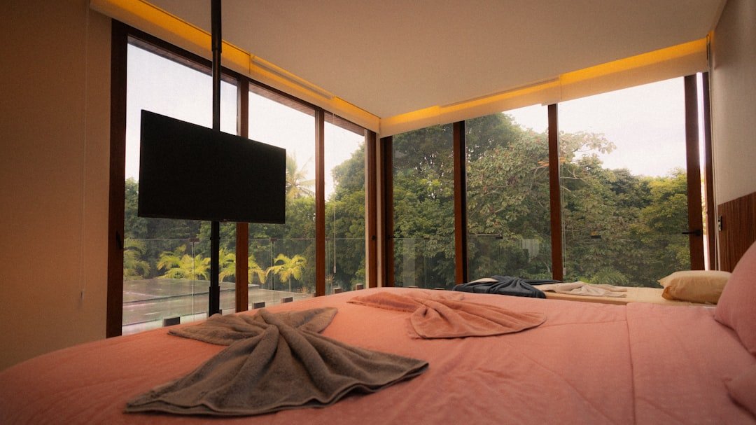 Bedroom with large windows overlooking a lush green forest