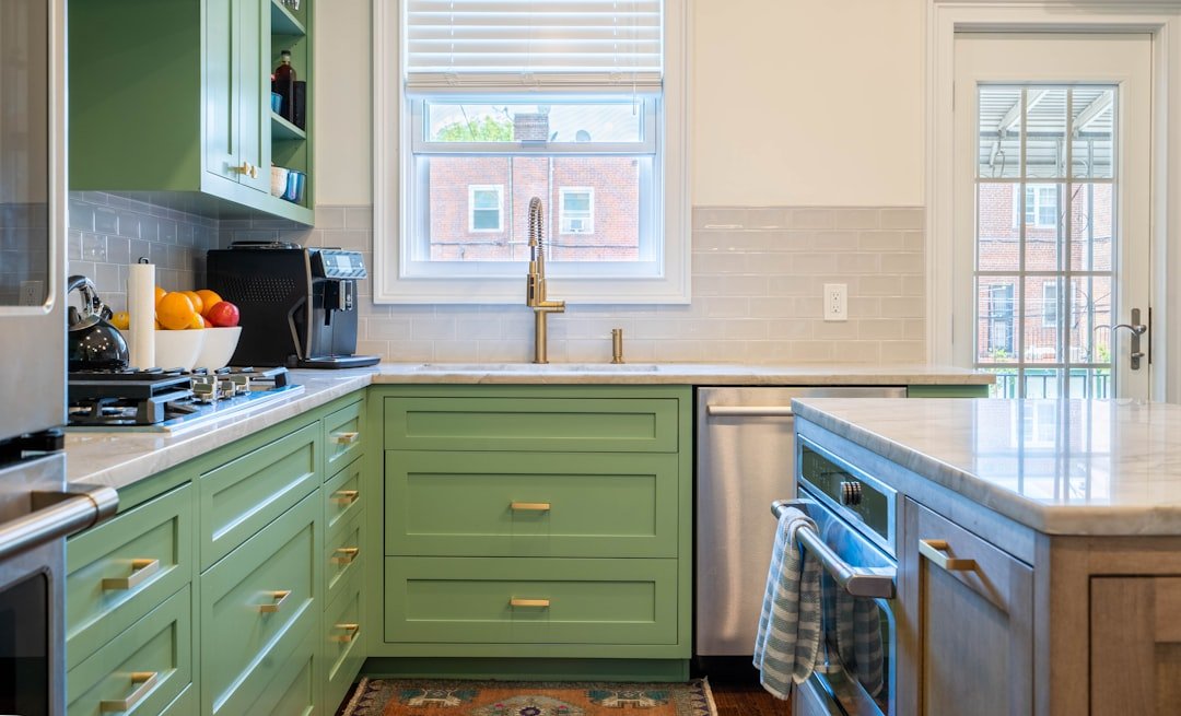 Green lower kitchen cabinets with white countertops, an example of adding color to a white kitchen