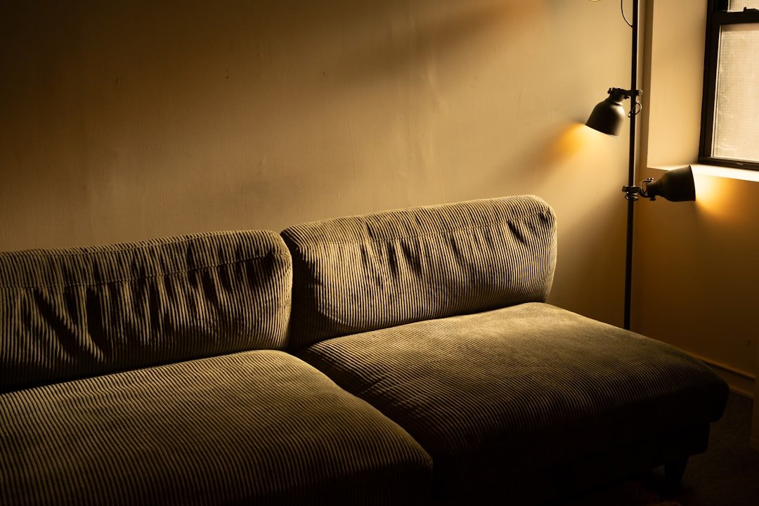 Dimly lit living room with a floor lamp creating a warm pool of light behind the sofa