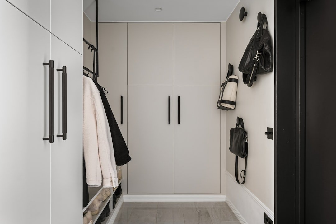 Narrow white hallway entryway with slim wall mounted storage and black accents