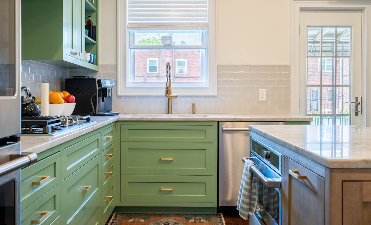 Kitchen with olive green cabinets, white countertops and brass hardware