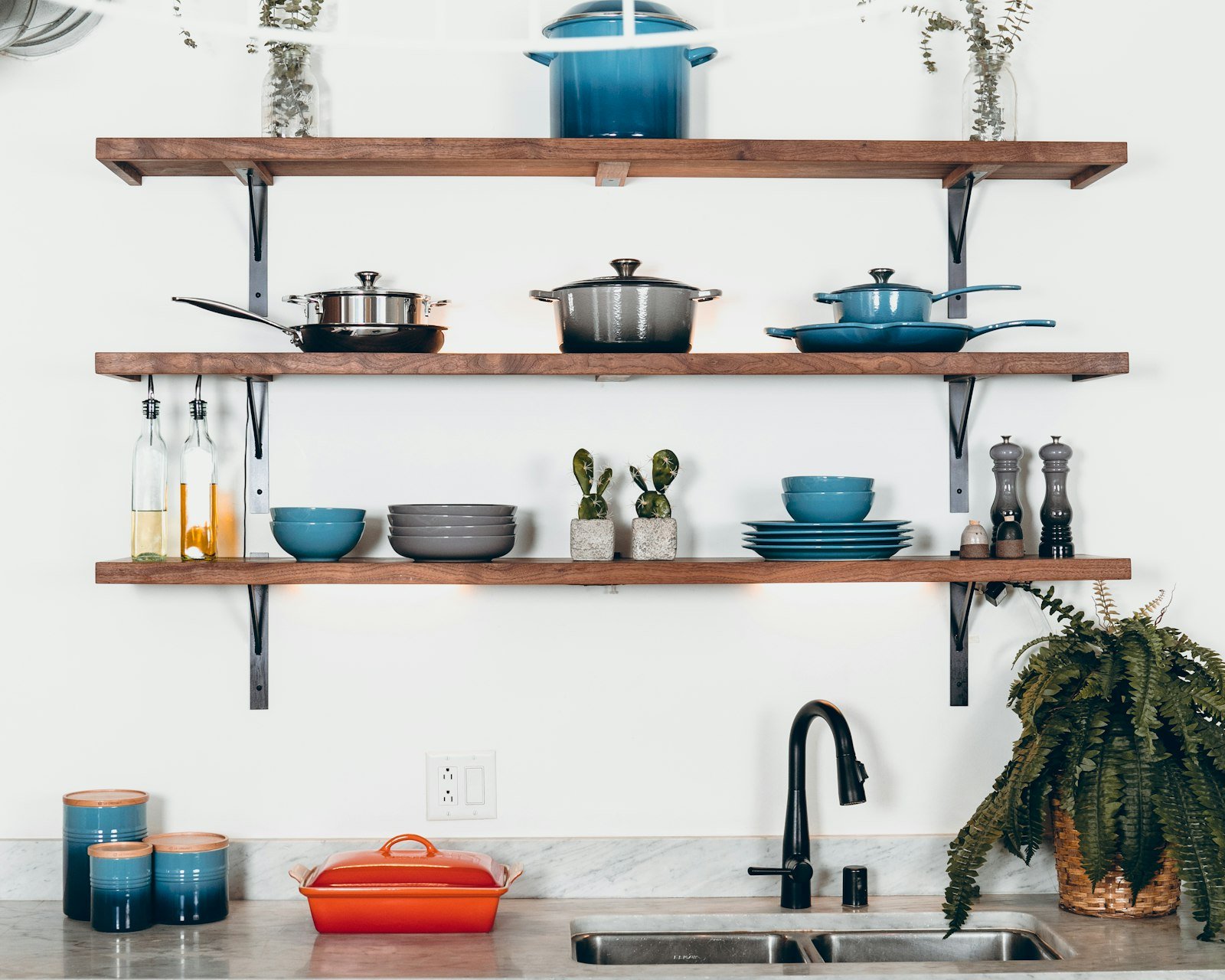 Small doses of color on open kitchen shelves with cookware and ceramics