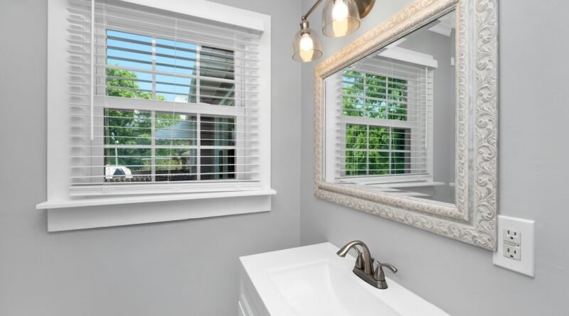 Small bathroom with soft light wall color, white sink and a window bringing in natural light
