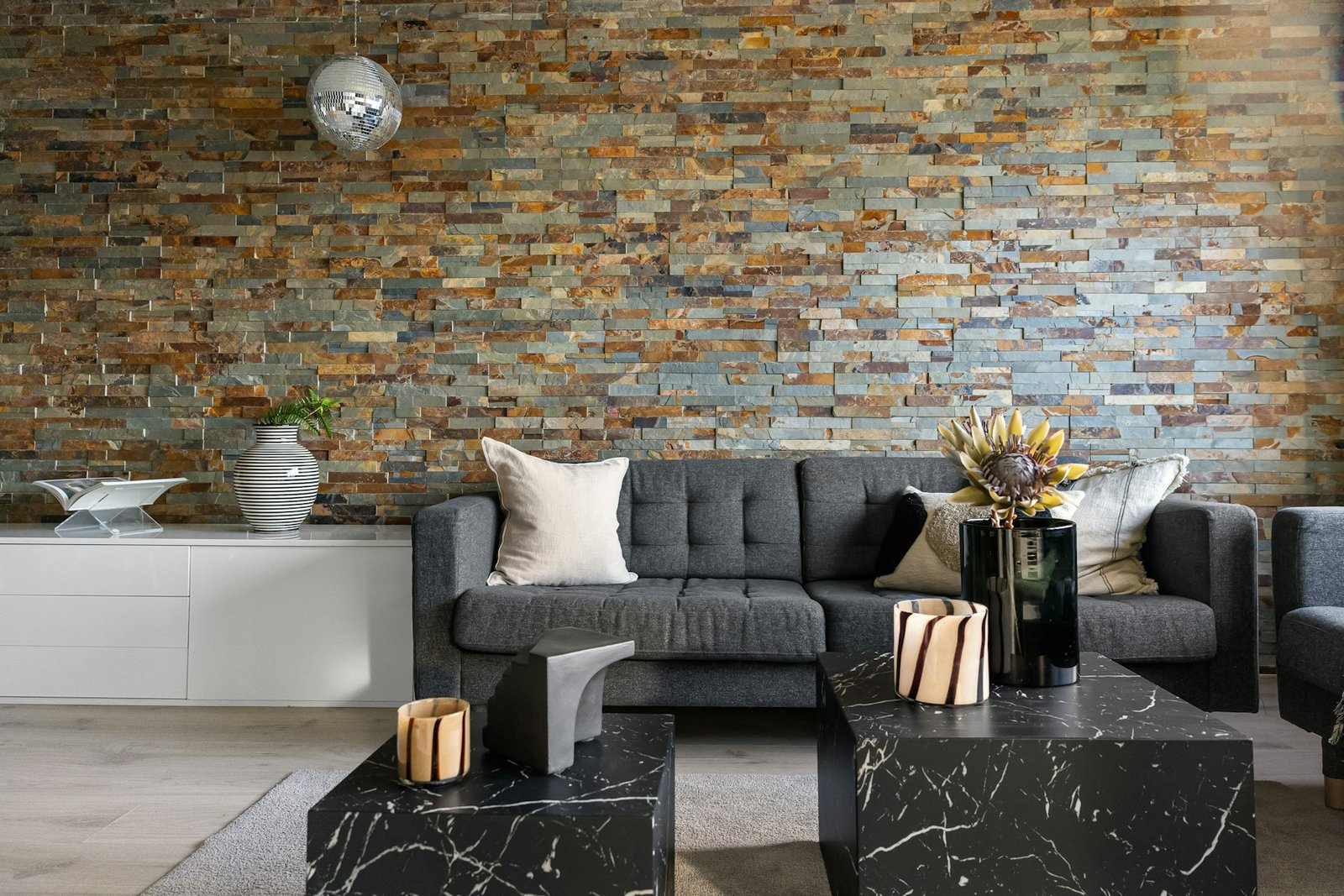 Warm living room with a textured stone wall, wood furniture and layered neutral decor