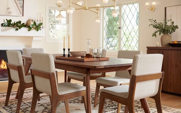 Warm dining room with a walnut table, upholstered chairs, patterned rug, and sculptural brass chandelier