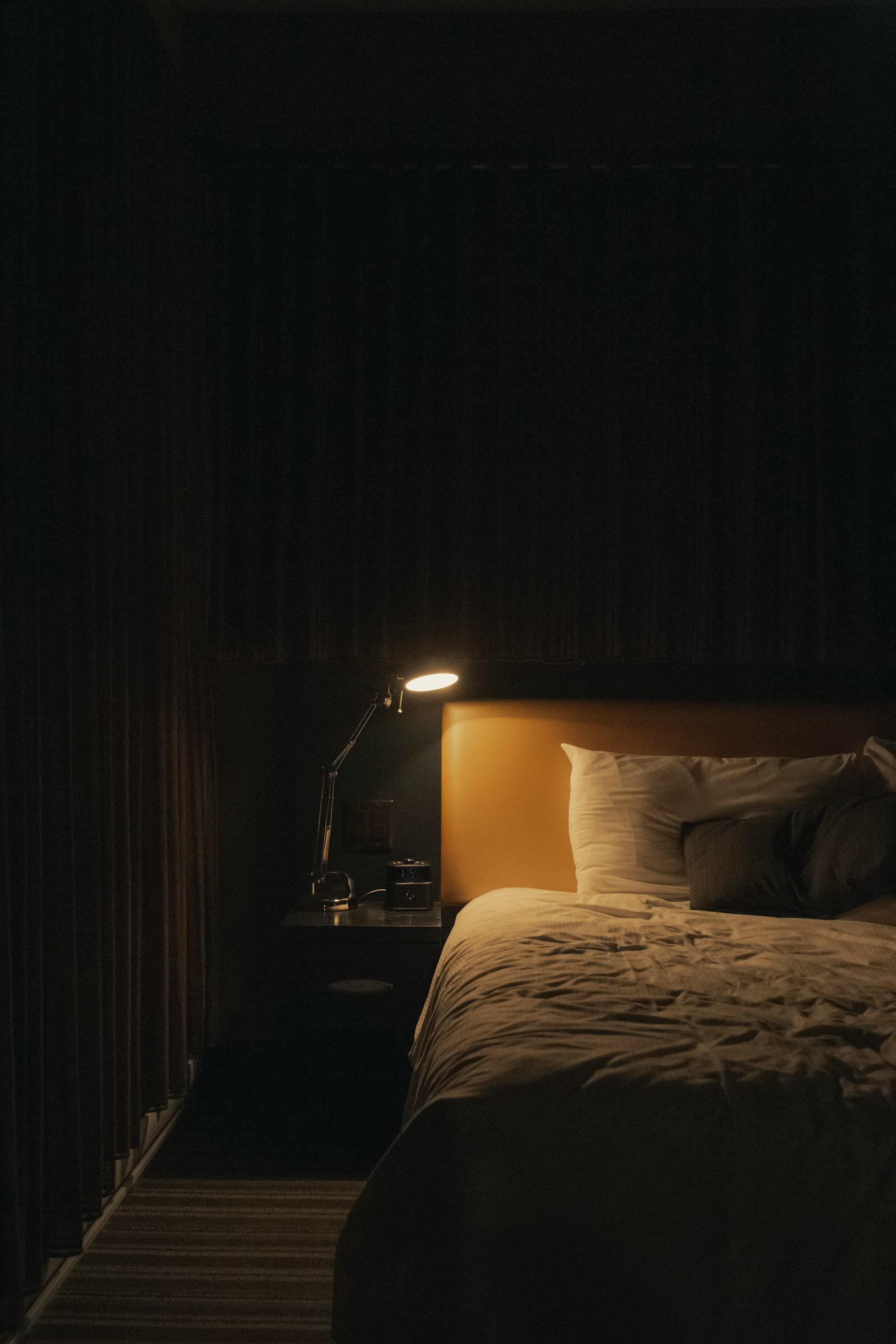 Warm bedside lamp glowing beside a bed, a cozy bedroom lighting idea