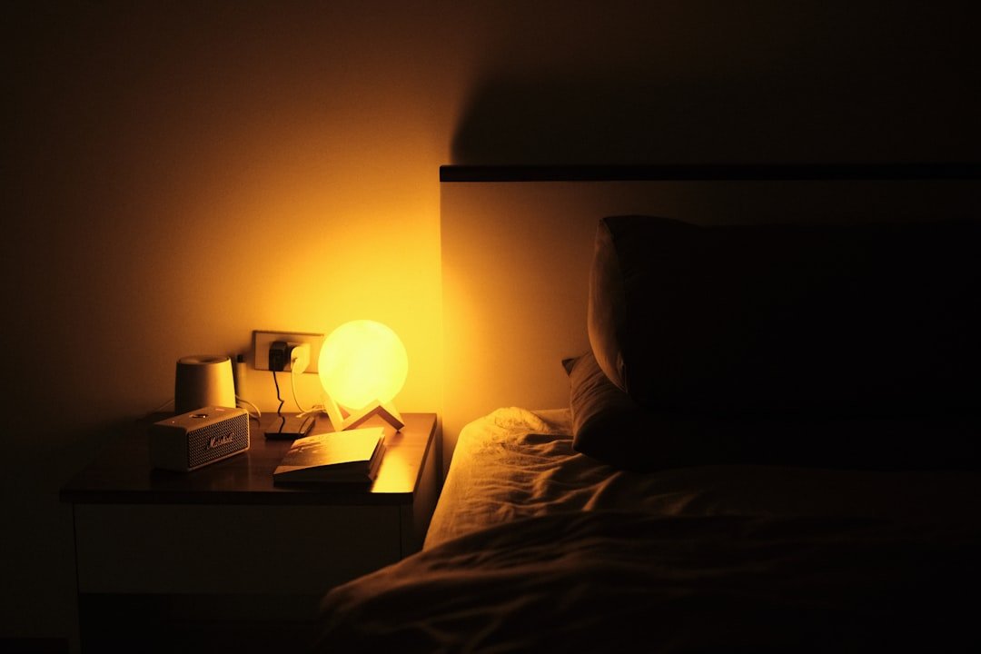 Warm bedside lamp lighting a nightstand in a small bedroom, an example of layered small bedroom lighting