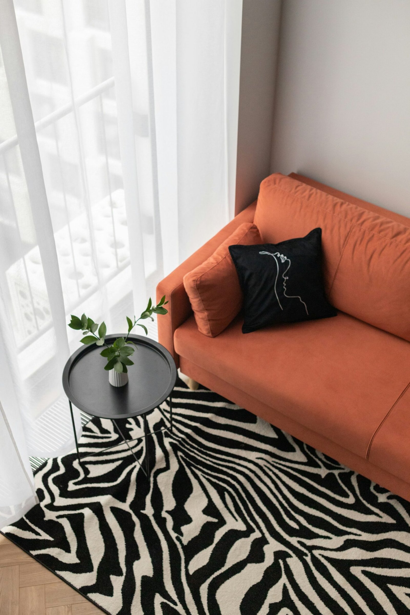 Orange sofa styled with a bold black and white patterned rug in a modern apartment