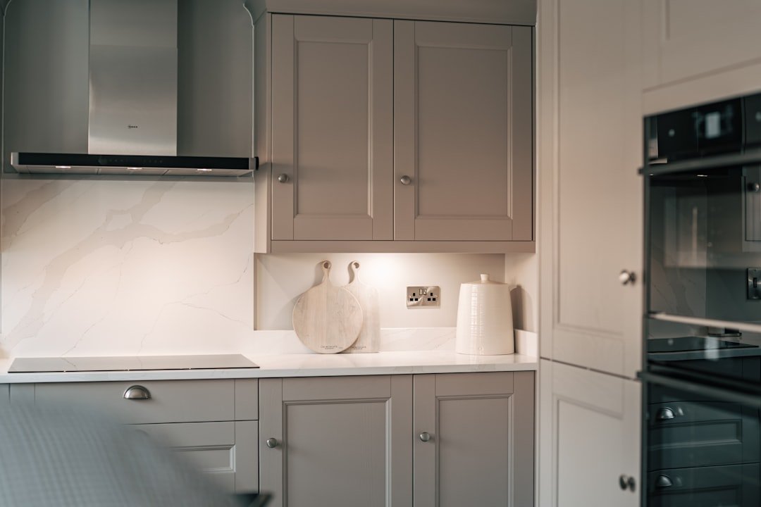 Narrow galley kitchen with white cabinets, black oven and a bright streamlined layout