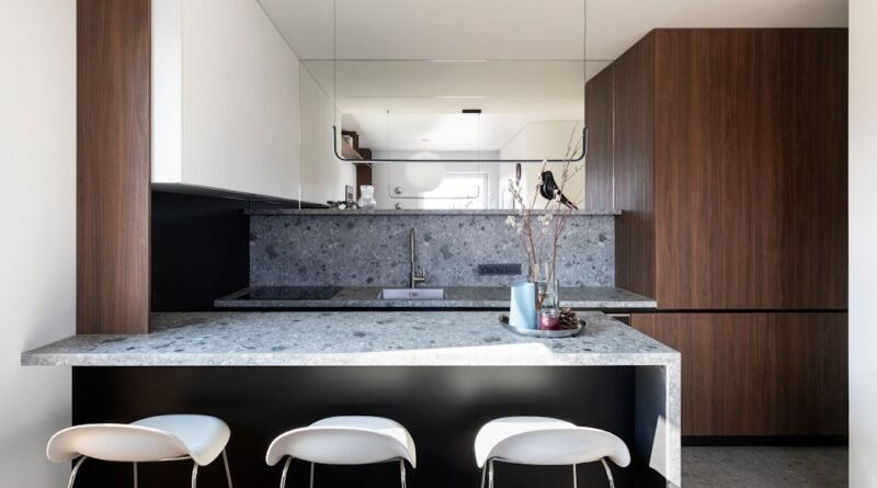 Small modern kitchen with dark wood cabinetry, terrazzo surfaces and warm wood flooring