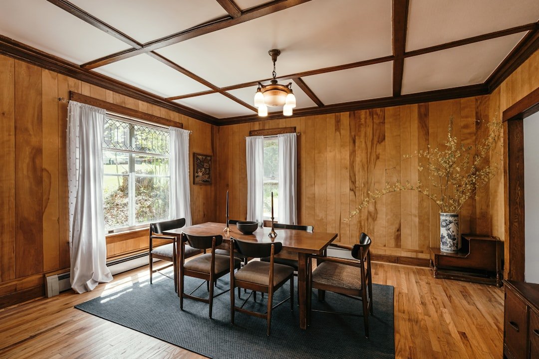 Dining room with decorative wall molding, warm wood furniture and layered neutral decor